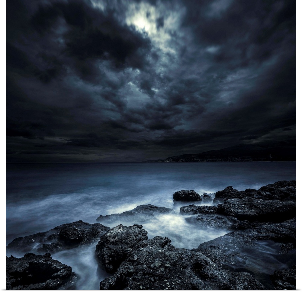 Black rocks protruding through rough seas with stormy clouds, Crete, Greece.