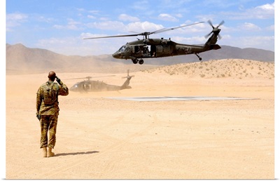 Brigade aviation officer salutes as a UH-60 Black Hawk helicopter lifts off