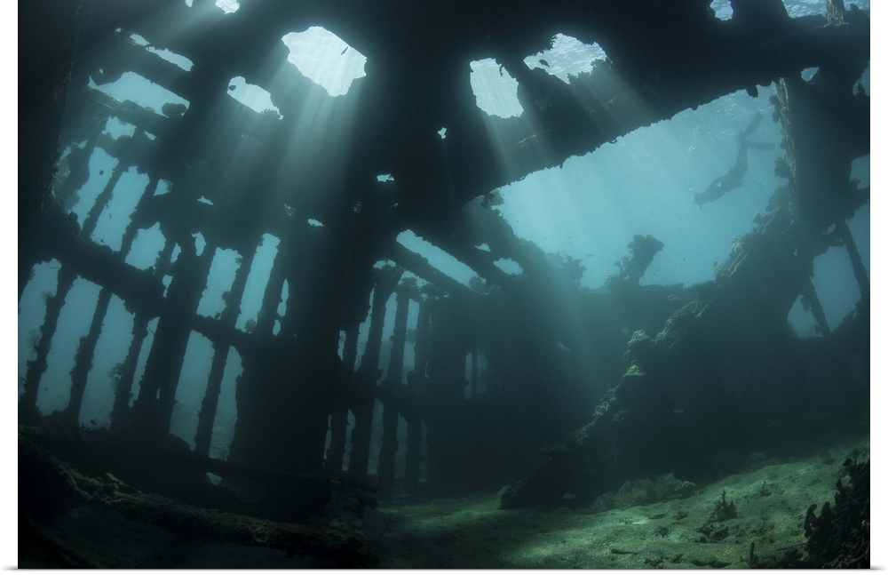 Bright sunlight pierces a shallow World War II shipwreck.