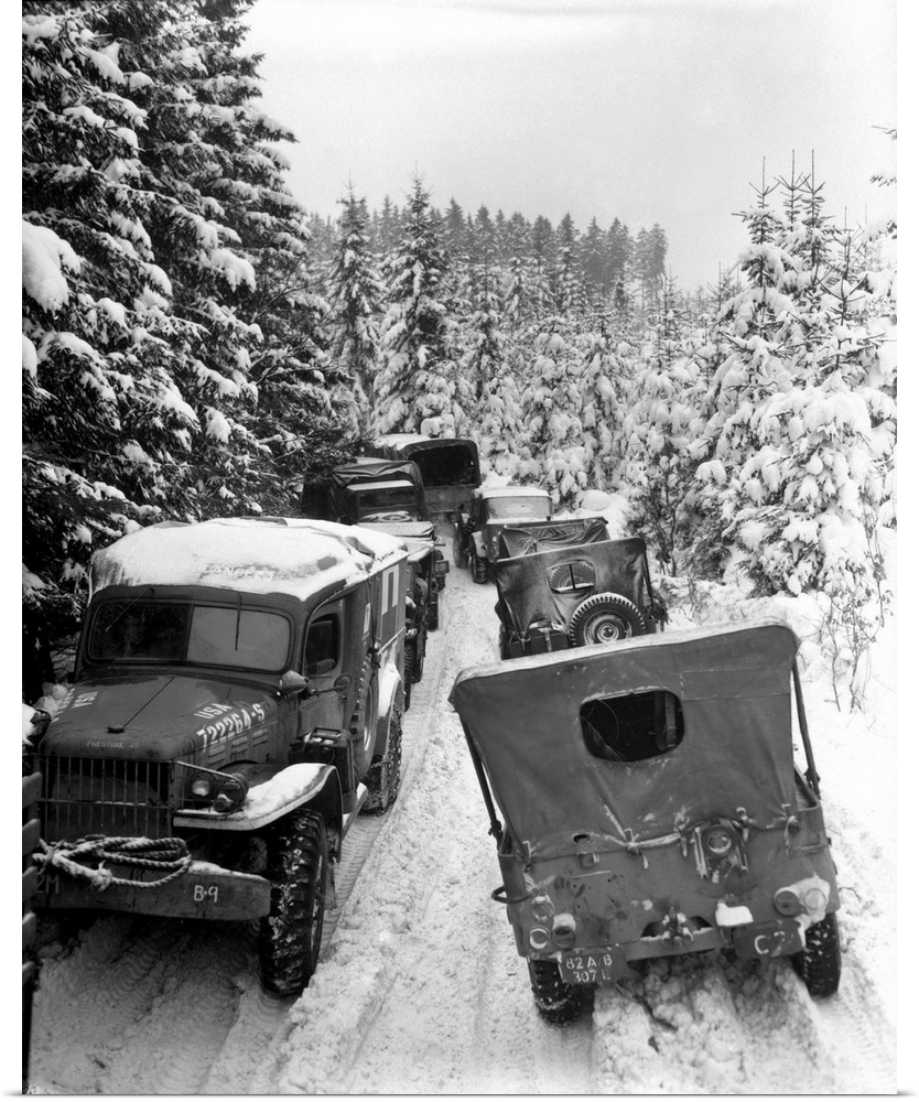 Deep snow banks on a narrow road halt military vehicles in Belgium, 1945.
