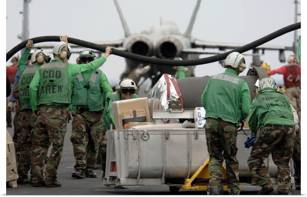 Delivery crew lift a fuel hose to help other Sailors move mail and supplies across the flight deck.