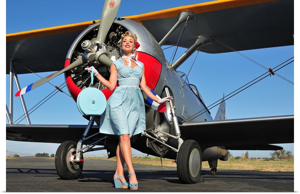 Elegant 1940's style pin-up girl standing in front of an F3F biplane.