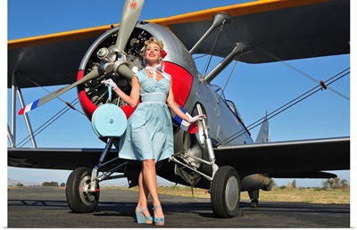 Elegant 1940's style pin-up girl standing in front of an F3F biplane