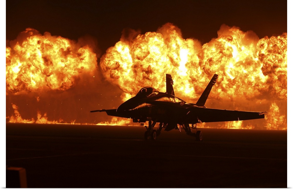 Flames explode behind an F/A-18 Hornet of the U.S. Navy Blue Angels.