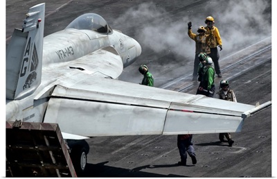 Flight deck crew position an F/A-18E Super Hornet into launch position