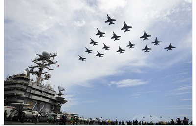 Helicopters and jets fly in formation above flight deck of USS Abraham Lincoln