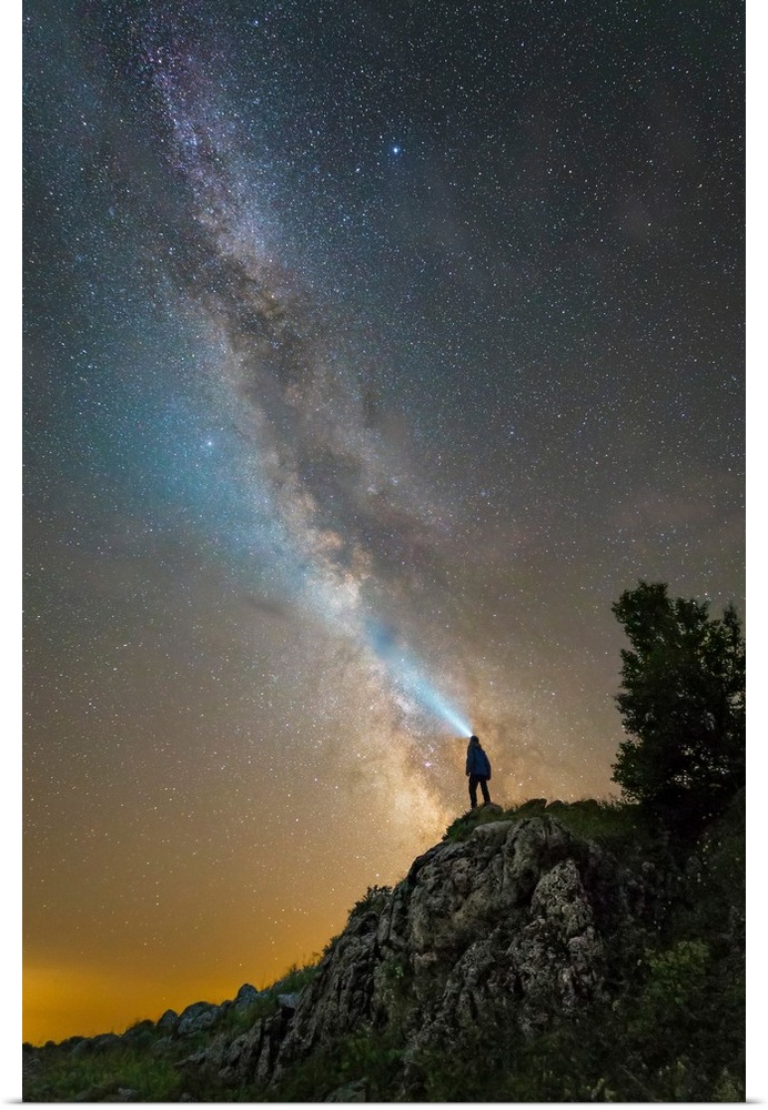 Man shining a flashlight on the Milky Way from atop a mountain in Russia.