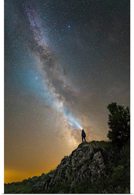 Man shining a flashlight on the Milky Way from atop a mountain in Russia
