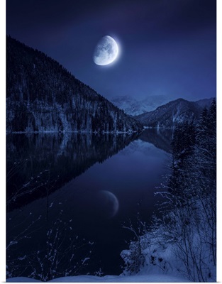 Moon rising over tranquil lake in misty mountains