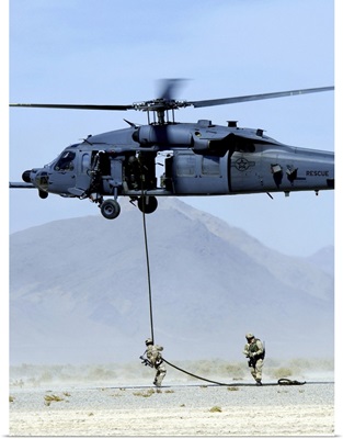 Pararescuemen descend from an HH-60 Pave Hawk helicopter