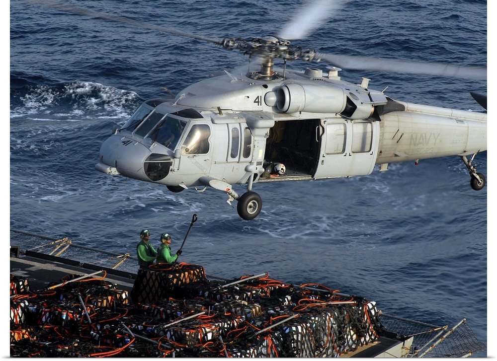 Sailors attach pallets of supplies to an MH-60S Knighthawk.