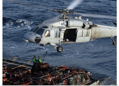 Sailors attach pallets of supplies to an MH-60S Knighthawk