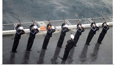 Sailors fire a 21-gun salute during a burial at sea ceremony