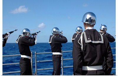Sailors fire a gun salute during a burialatsea