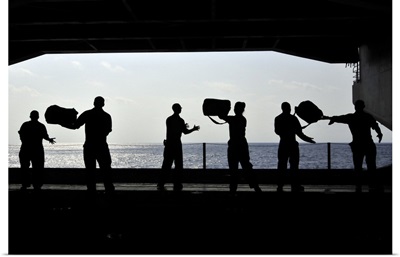 Sailors pass supplies to each other in the hangar bay of USS Ronald Reagan