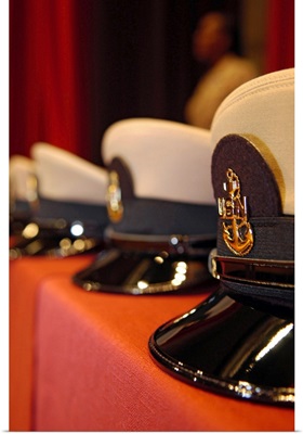 Several chief petty officers combination covers lined up on a table