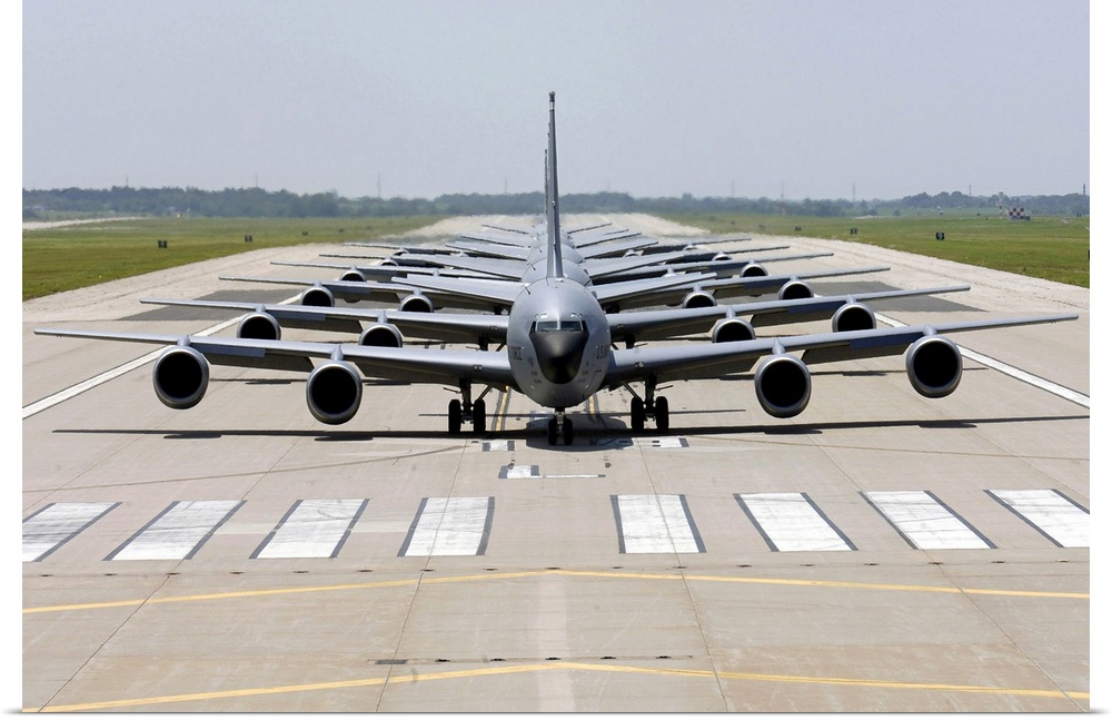 Photograph of several large Stratotanker airplanes perfectly lined up in a row on a runway.