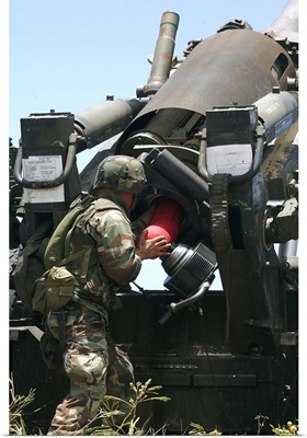 Soldier loads a charge round behind the ammunition round of the Howitzer 150 gun