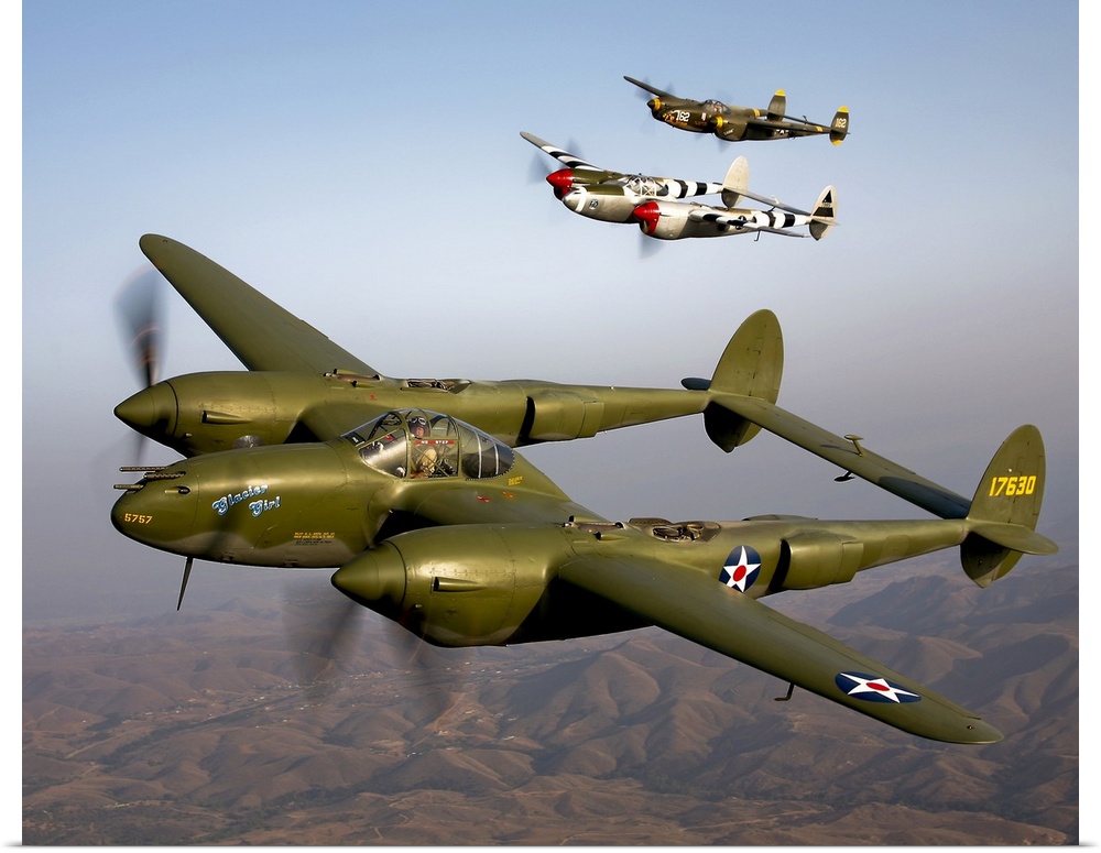 Three vintage military aircrafts are photographed in the sky as they fly high over mountainous terrain in California.