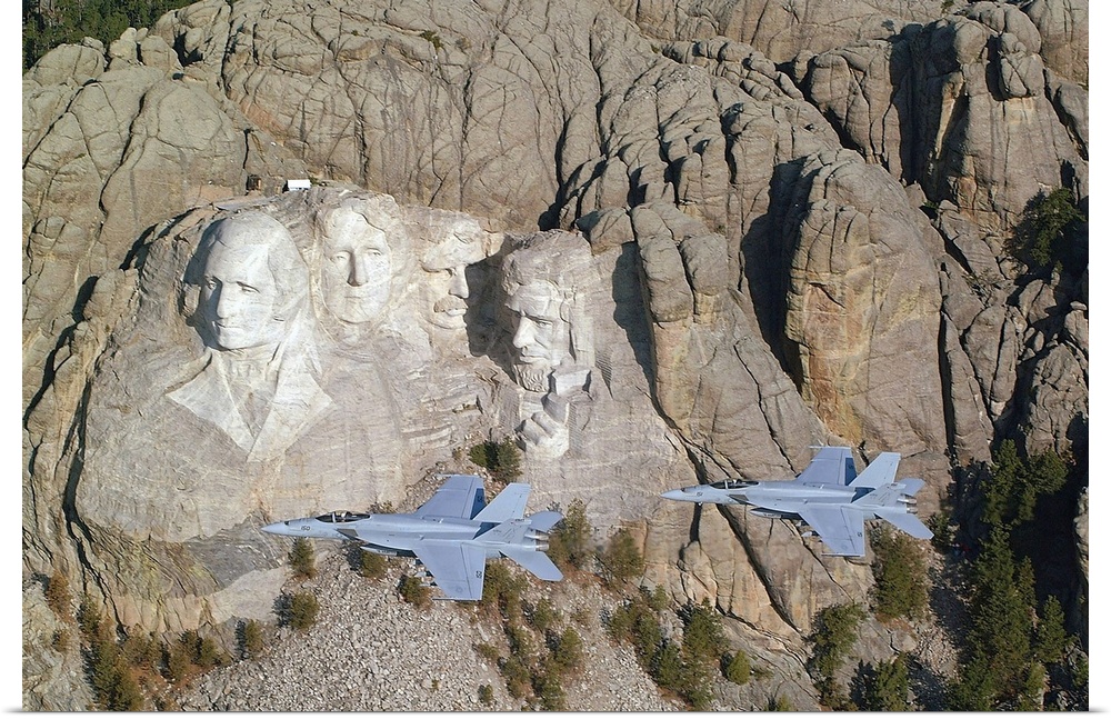Two military aircrafts are photographed flying by Mount Rushmore.