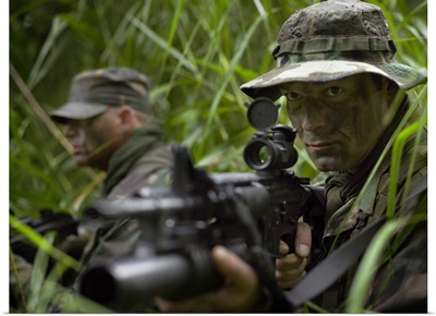 U.S. Special Forces soldiers patrol through tall grass during combat