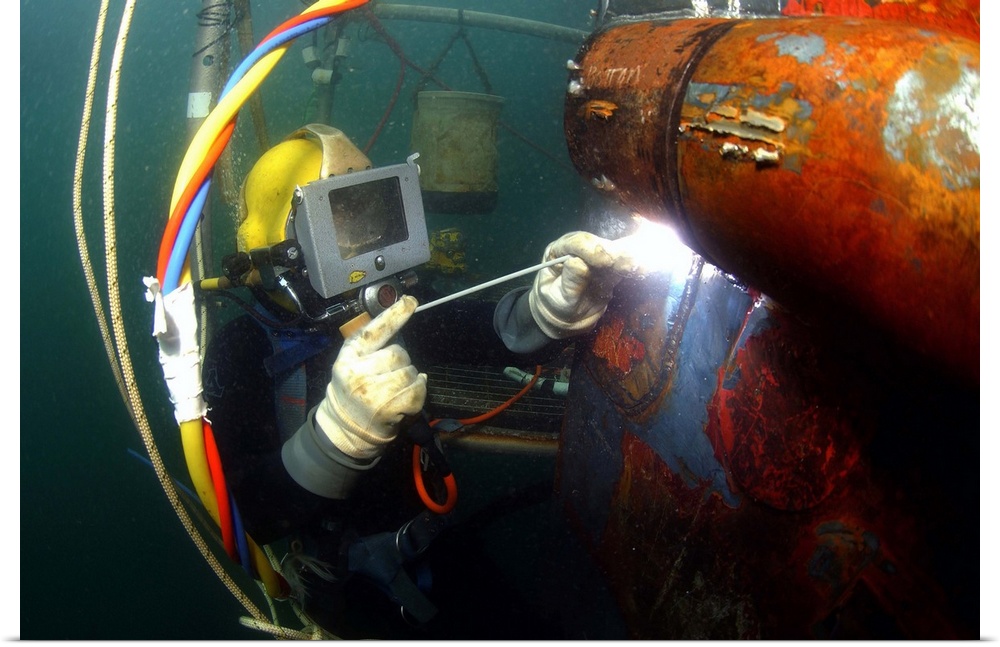 U.S. Navy Diver welds a repair patch on the submerged bow of the USS Ogden.