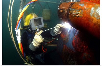 US Navy Diver welds a repair patch on the submerged bow of the USS Ogden