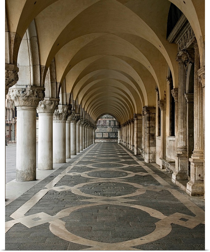 Photograph of a walkway in the Ducale Palace in Urbino, Italy under ornate arches.