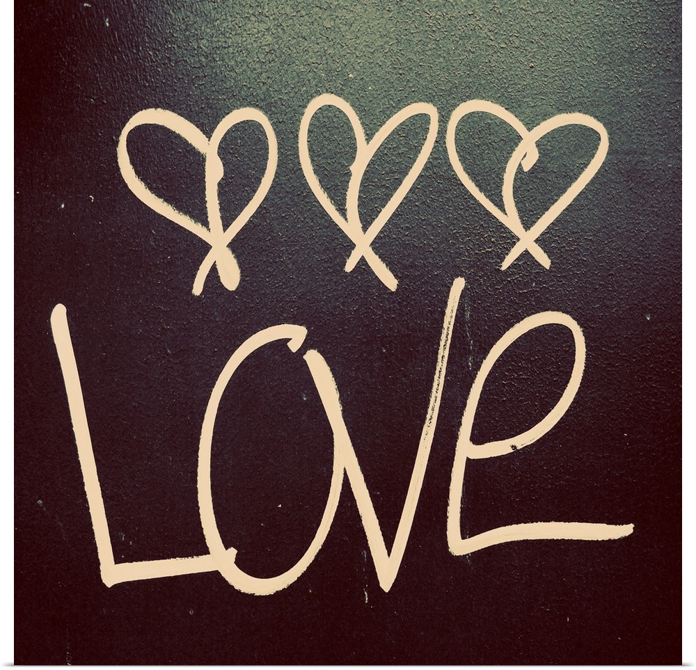 The word "Love" with three little hearts above written on a dark surface.