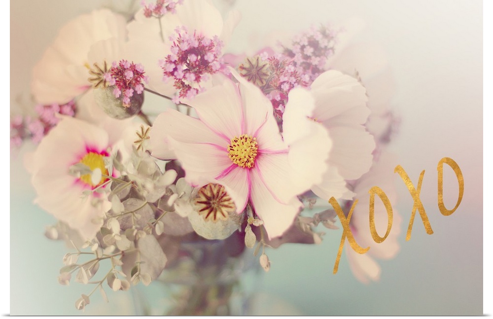 Soft, pink toned photograph of flowers arranged in a vase with "XOXO" written in gold on the side.