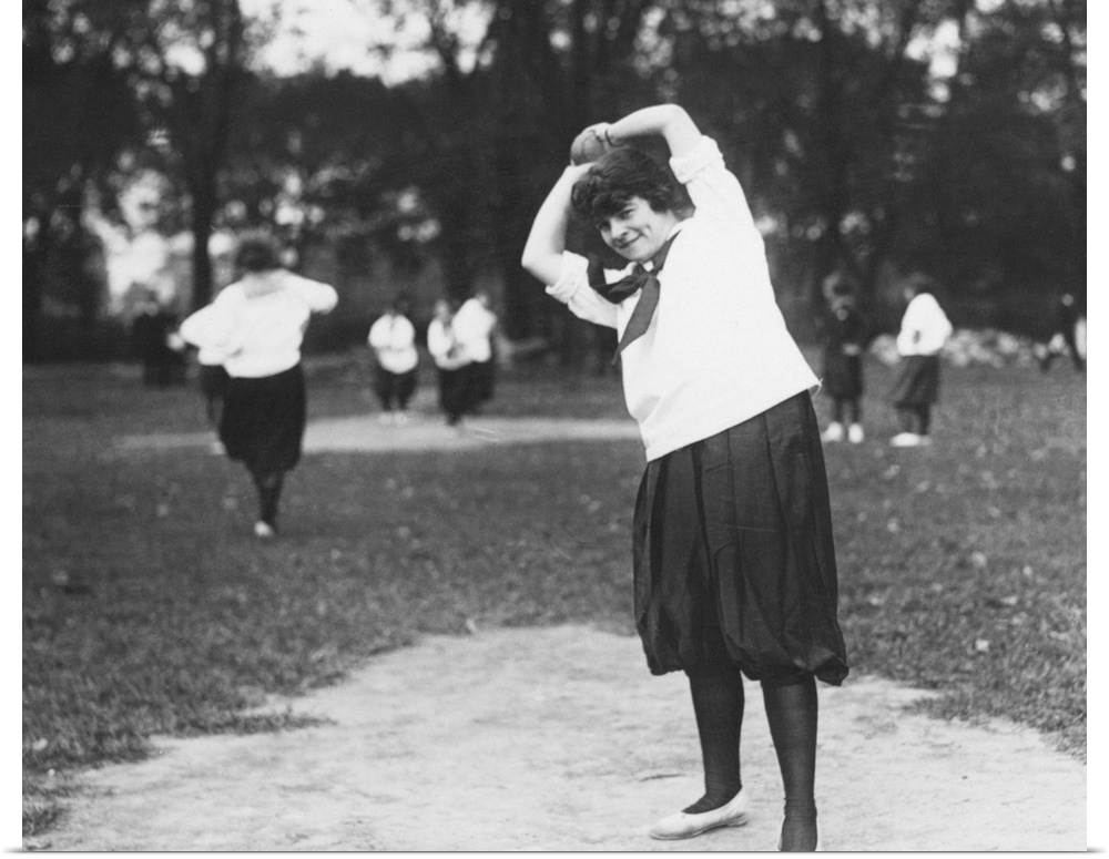 A woman on the pitcher's mound preparing to throw the ball during a softball game, c1920.