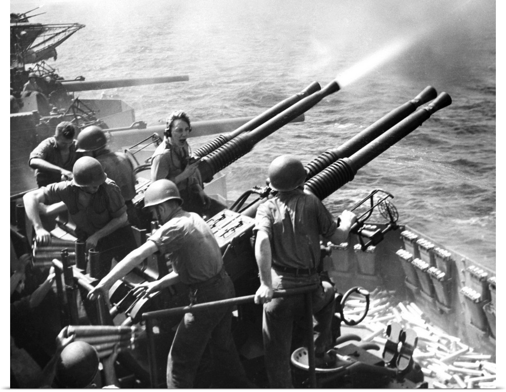 Crew members on board a U.S. Navy aircraft carrier fire anti-aircraft guns at Japanese planes in the Pacific Ocean, 1943.