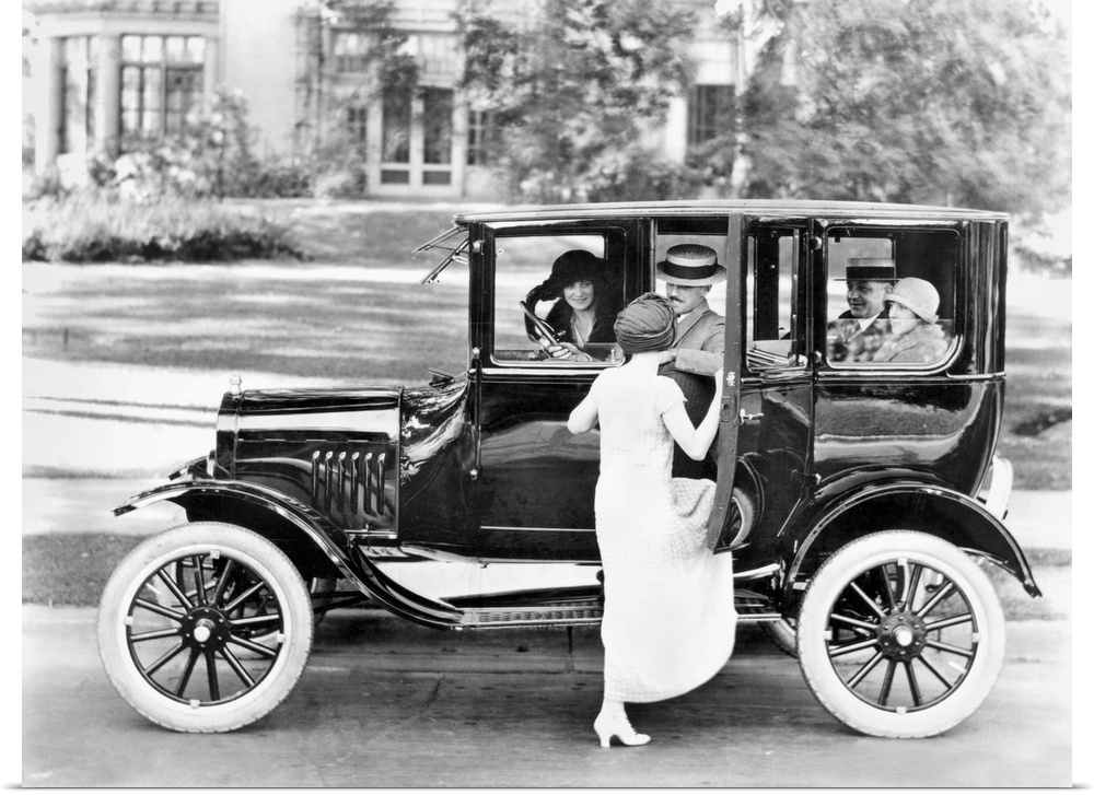 A woman getting into a Ford Sedan with four other passengers. Photograph, c1923.