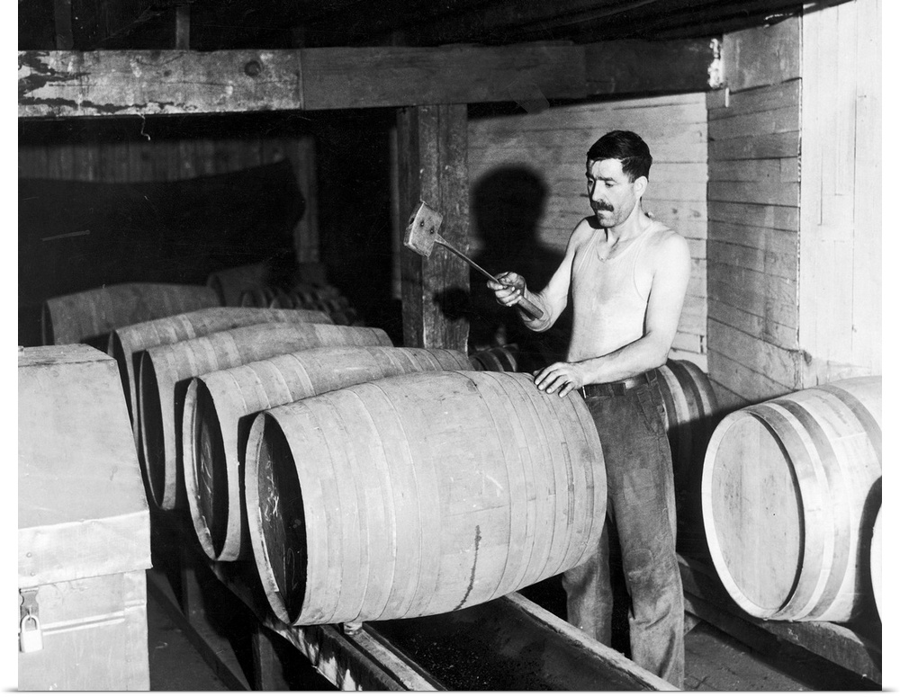 In preparation for the repeal of prohibition, a worker empties barrels of whiskey into a container for bottling at the Jos...