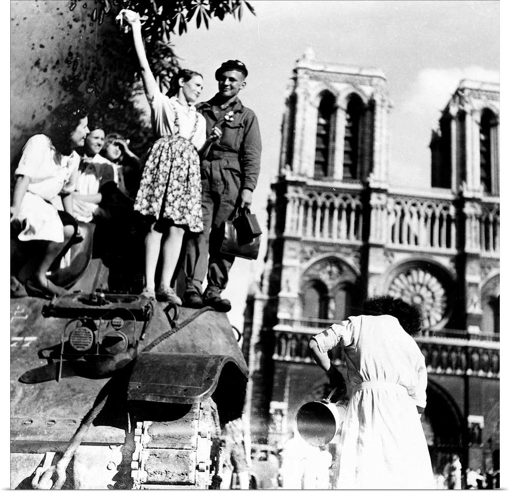 Young Parisian women join soldiers on a British tank, at Notre Dame Cathedral, after the liberation of the city by Allied ...