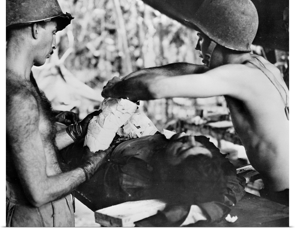 Medics operating on a wounded American soldier in New Guinea. Photograph, c1943.