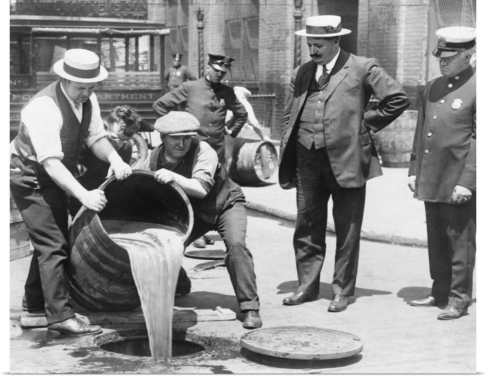 New York City Deputy Police Commissioner, John A. Leach (right), watches agents pour liquor into a sewer after a raid, c1921.