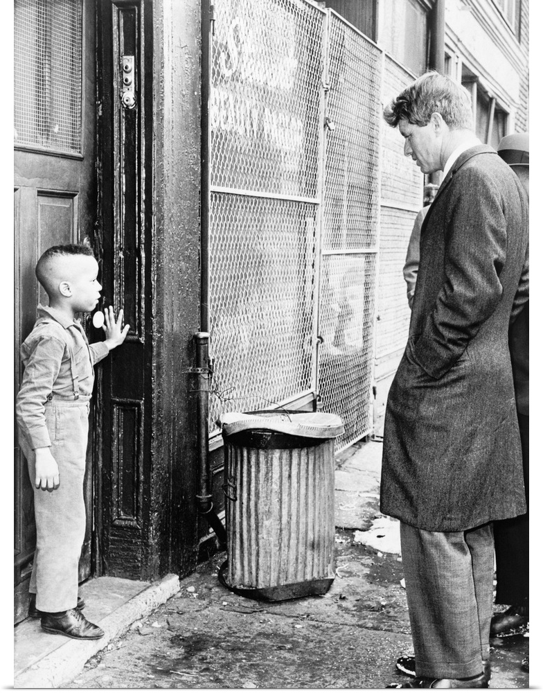 (1925-1968). American lawyer and politician. Senator Kennedy discussing school with a young boy in front of his home on Ga...