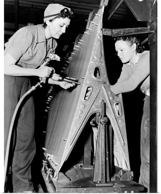 Two women riveting a piece of machinery at an American bomber plant during World War II