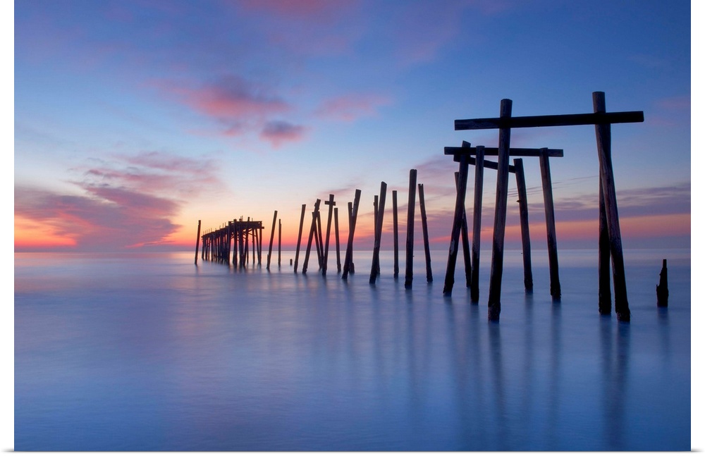 Old wooden pilings from a long-gone pier in the sea off of Ocean City, New Jersey, at dawn.