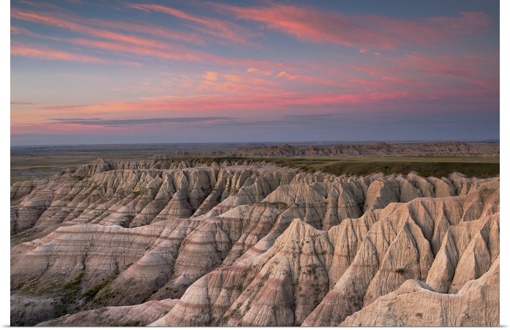 Pink clouds at dawn over the pointed rocky landscape of the South Dakota badlands.