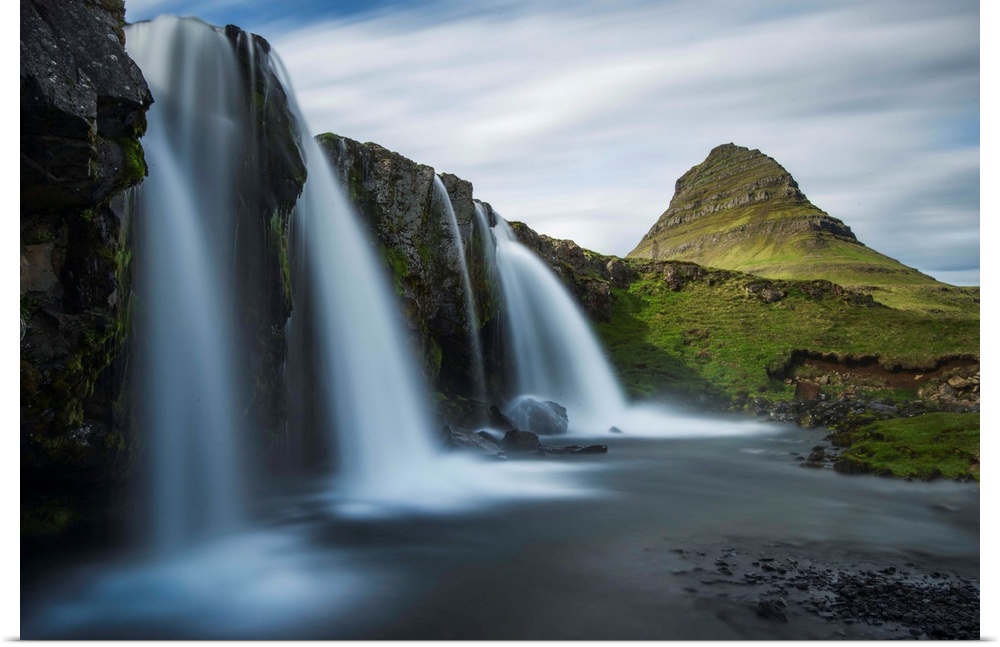 Glacial waterfall in Iceland with a view of Kirkjufell mountain in the distance.