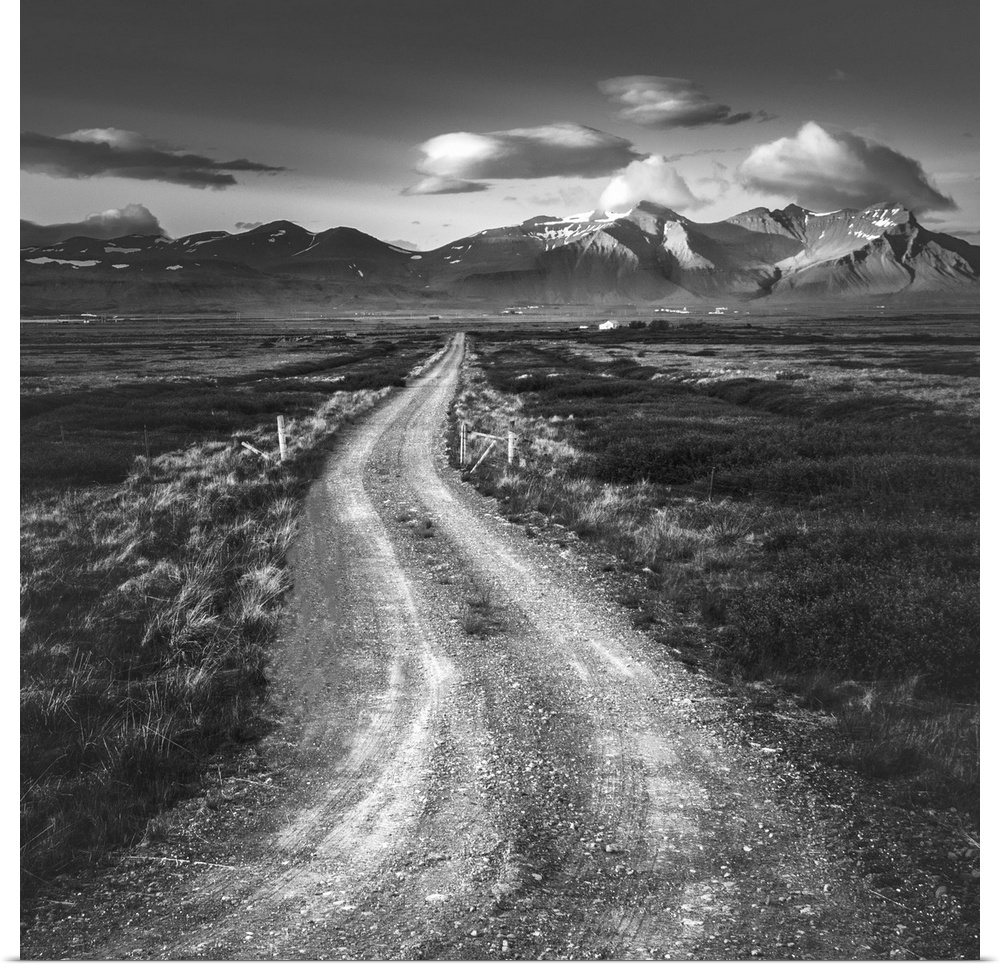 Black and white photo of a path leading to tall mountains on the horizon.