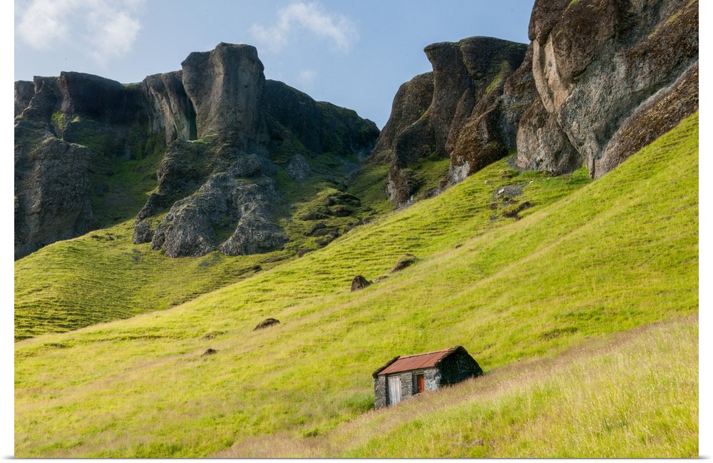 Oddly shaped rock formations emerging from the green landscape with a small house.