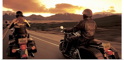 A couple ride their motorcyles alongside of each other while cruising at sunset