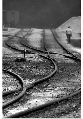 A man walking beside curving railway tracks