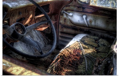 A wrecked old car with driving wheel and broken seat