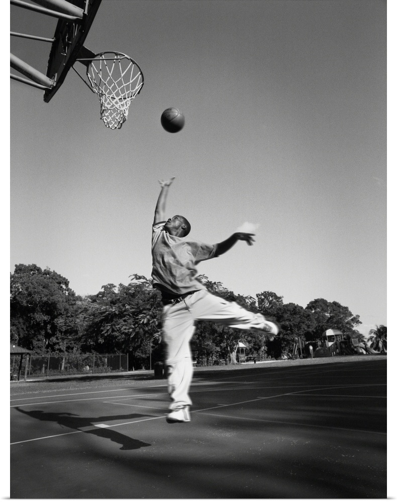 A young african-american boy gets air while playing basketball at his school
