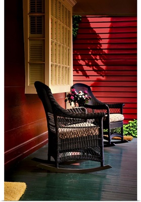 An American front porch with wooden boarding and two whicker rocking chairs