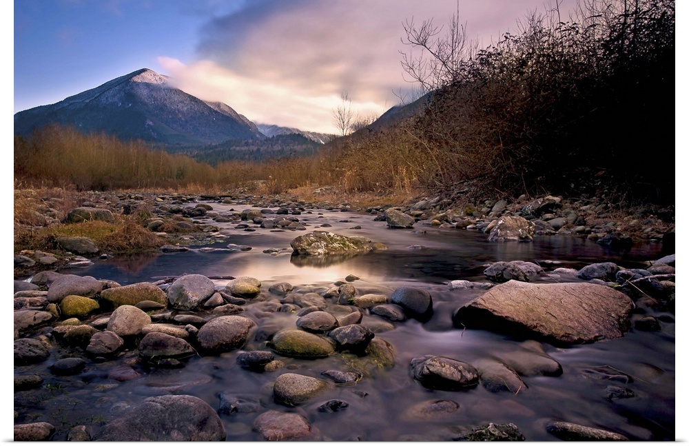 A rocky river overlooking a mountain at sunset.